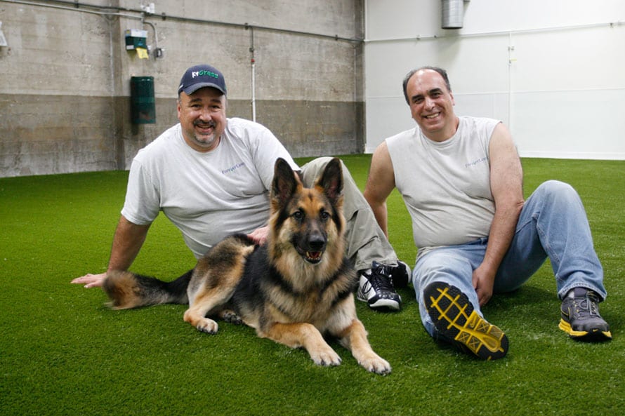 Ken and Jim Karmie sitting on K9Grass with a german shephard.